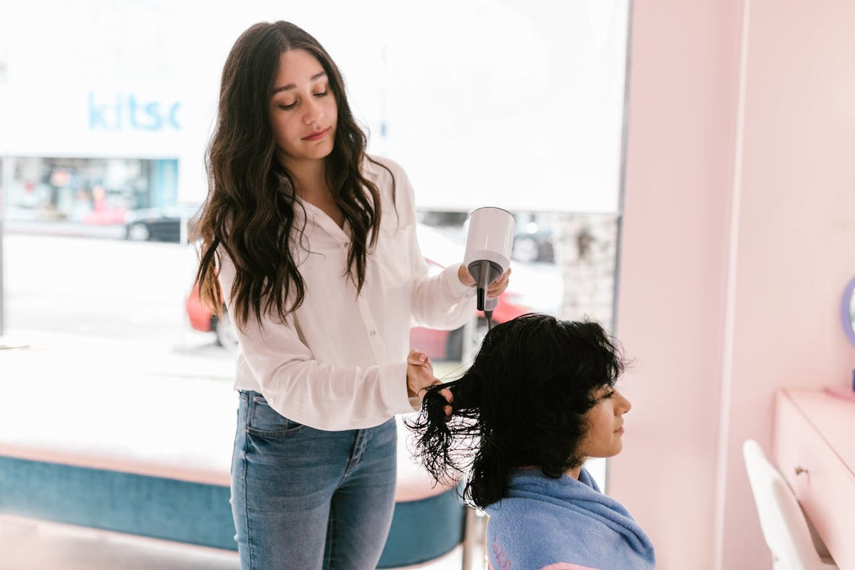 Woman styling another woman's hair in a salon setting