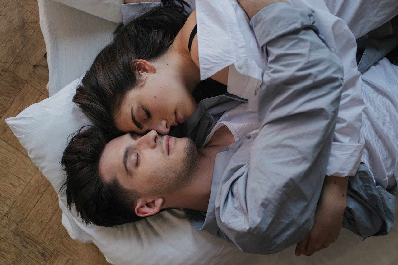 Healthy man and woman lying on a bed, embracing each other.